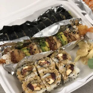a variety of sushi in a styrofoam container