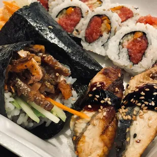 a variety of sushi and rolls in a styrofoam container