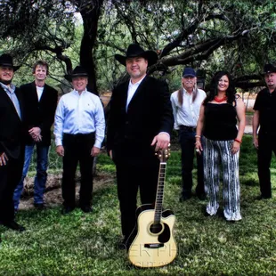 a group of men and women standing under a tree