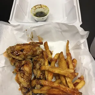 chicken wings and french fries in a styrofoam container