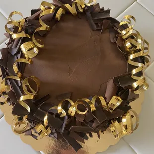 a chocolate cake decorated with gold ribbons