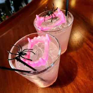 two glasses of pink cocktail with spider decorations