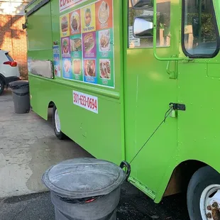 a green food truck parked on the side of the road