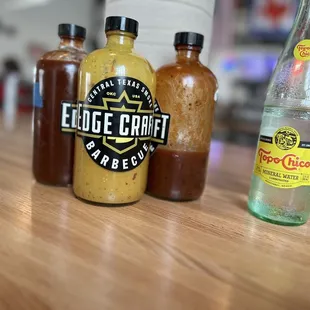 three bottles of sauce on a table