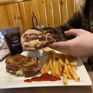 a person holding a sandwich and french fries