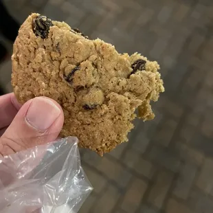 a hand holding a cookie with a bite taken out of it