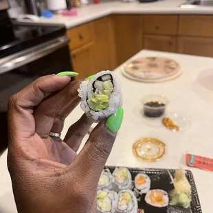 a hand holding a piece of sushi