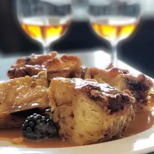 a plate of bread pudding and two glasses of wine