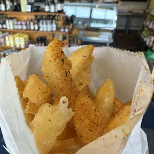 a hand holding a basket of fried potatoes