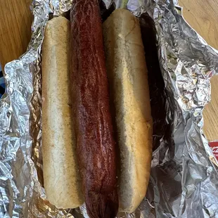 two hot dogs wrapped in tin foil