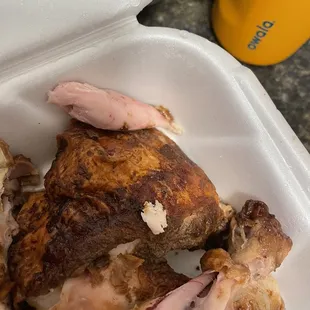 a close up of a chicken and potatoes in a styrofoam container
