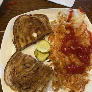 Classic Reuben Sandwich without sauerkraut in photo and side of hash browns with customer added ketchup.