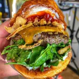 The Truffle Crunch Burger - House brisket patty, truffle spread, arugula, sharp cheddar, smoked jalapeno ketchup, buttermilk fried shallots