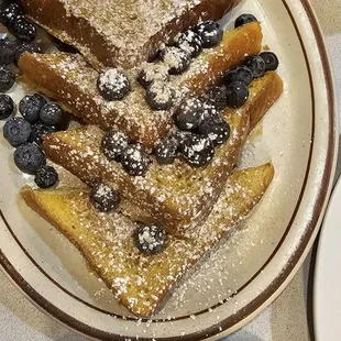 a plate of french toast with blueberries and bananas