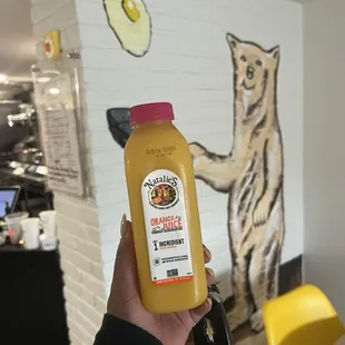 a person holding a bottle of orange juice