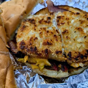 Bacon, egg, and cheese sandwich with hash browns opened up with bread to the side