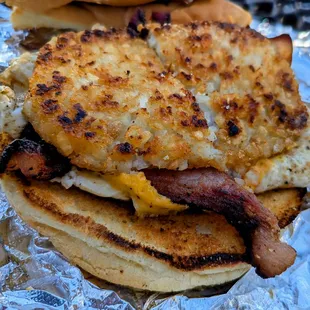 Bacon, egg, and cheese sandwich with hash browns opened up