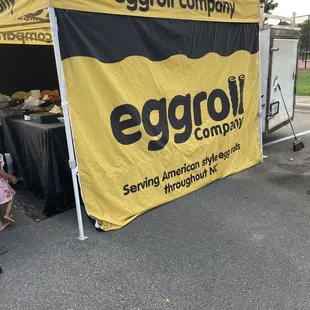 an eggroll company tent with a little girl standing in front of it