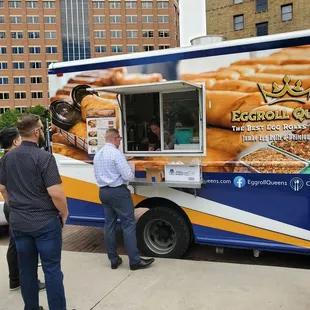 two people standing in front of a food truck