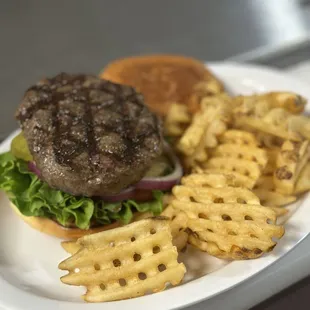 a hamburger and waffle fries on a plate