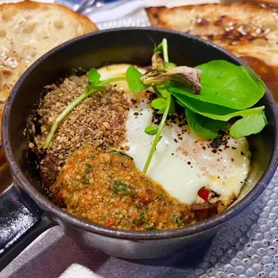 SHIRRED DUKKAH: lamb merguez, raisin, dukkah, hazelnut romesco, baked eggs, &amp; grilled baguette