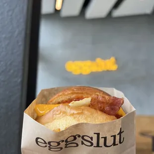a bacon and cheese sandwich in a paper bag