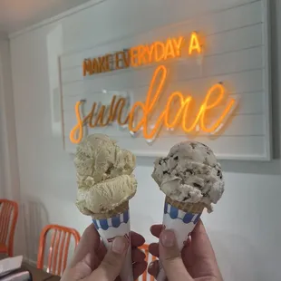 two ice cream cones in front of a neon sign