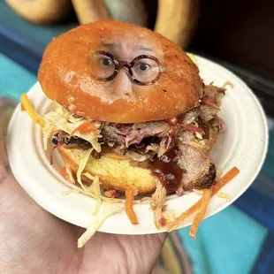 a hand holding a plate with a sandwich on it