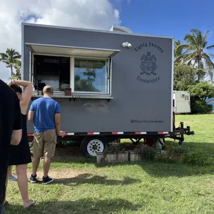 people standing outside of a food truck