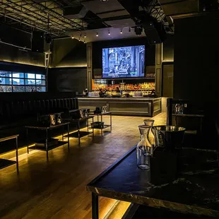 a bar with black leather seating and a flat screen tv