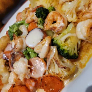 a plate of food with shrimp, broccoli and carrots