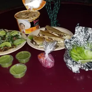 Tacos, quesabirria tacos, birria ramen, salsas, pickled onions, limes and cucumbers