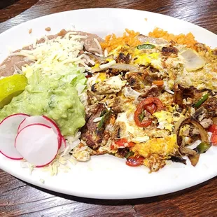Machaca - scrambled eggs with carnitas, bell peppers, tomatoes, and onions. Served with rice, beans, guacamole, and tortillas.