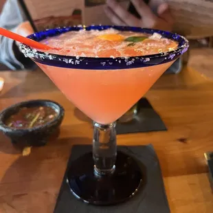 a pink cocktail in a glass with a blue rim