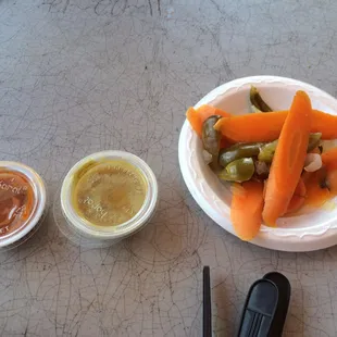 Two hot sauces offered and spiced pickled carrots with peppers &amp; onions