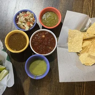Limes, jalapeño sour cream, taco sauce, salsa, green chile salsa, avocado salsa, and pickled cabbage, chips.