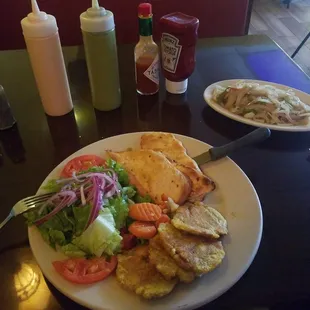 Grilled chicken with side salad, tostones and side of grilled onions