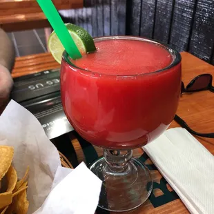 a red drink with a lime garnish