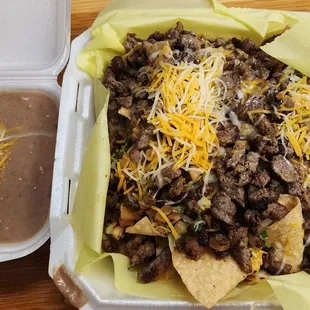a tray of nachos and a container of quesadilla