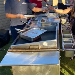 a group of people standing around a buffet table
