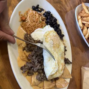 Chipotle Chilaquiles with eggs over easy and carne asada added to it.