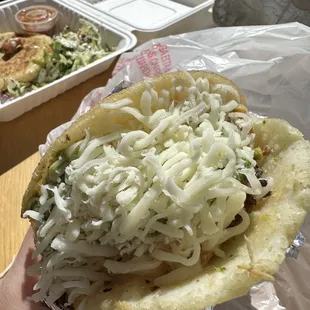 a person holding a pita with shredded cheese