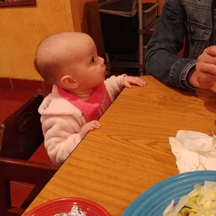 a baby sitting at a table with food