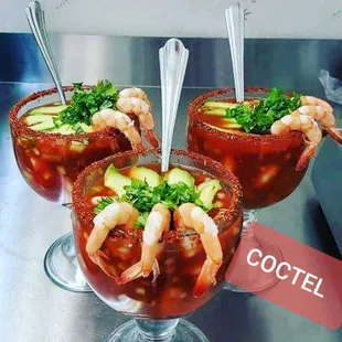 three glasses of bloody cocktail with shrimp, cucumber, and garnish
