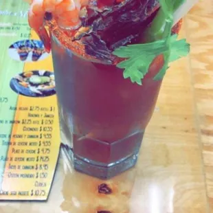 a bloody drink with shrimp and celery garnish