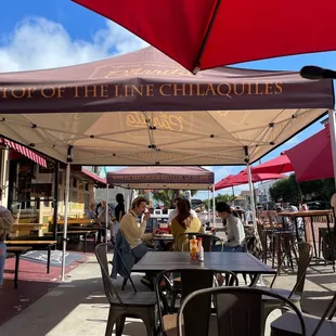 people sitting at tables under umbrellas