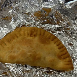 a baked empanada on aluminum foil
