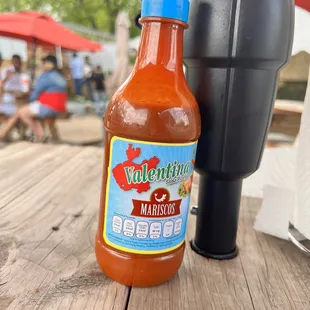 a bottle of hot sauce on a picnic table