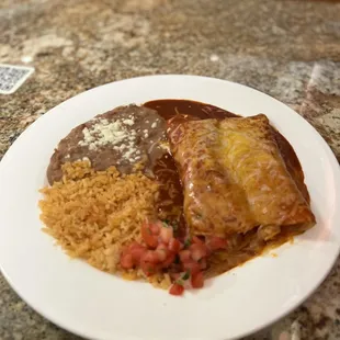 Red sauce Enchiladas with refried beans and rice.