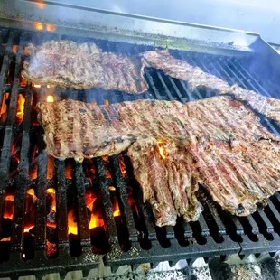 steaks cooking on a grill